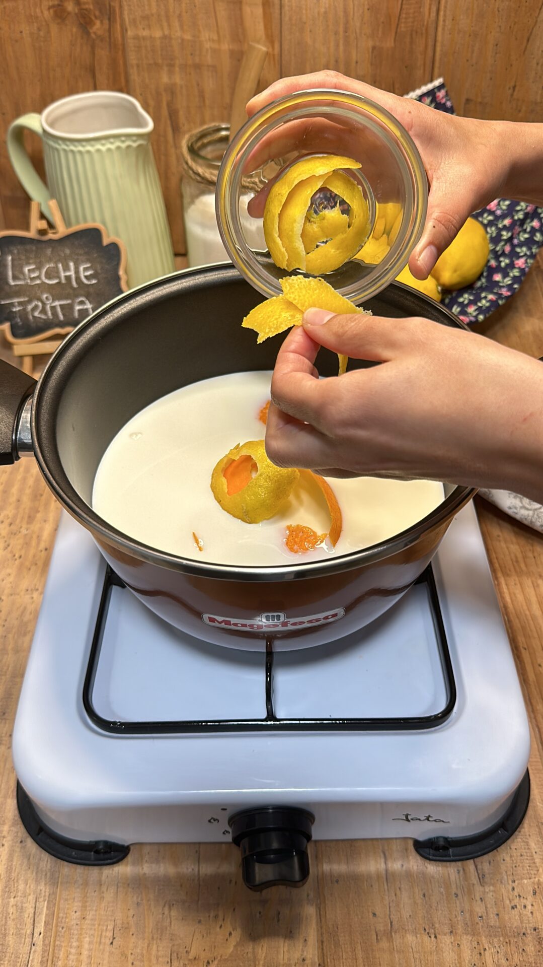 Llevamos la leche a un cazo y añadimos las pieles de naranja y limón